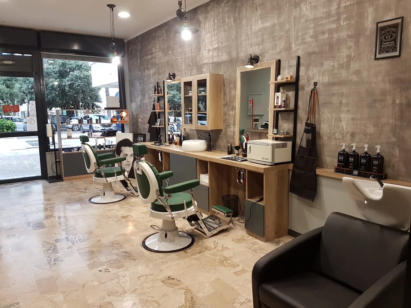 La sala di Barber Mood: poltrone da barbiere verdi, banco in rovere e pareti in cemento